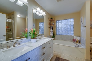 A bathroom with a double sink vanity, a large mirror, and a bathtub.