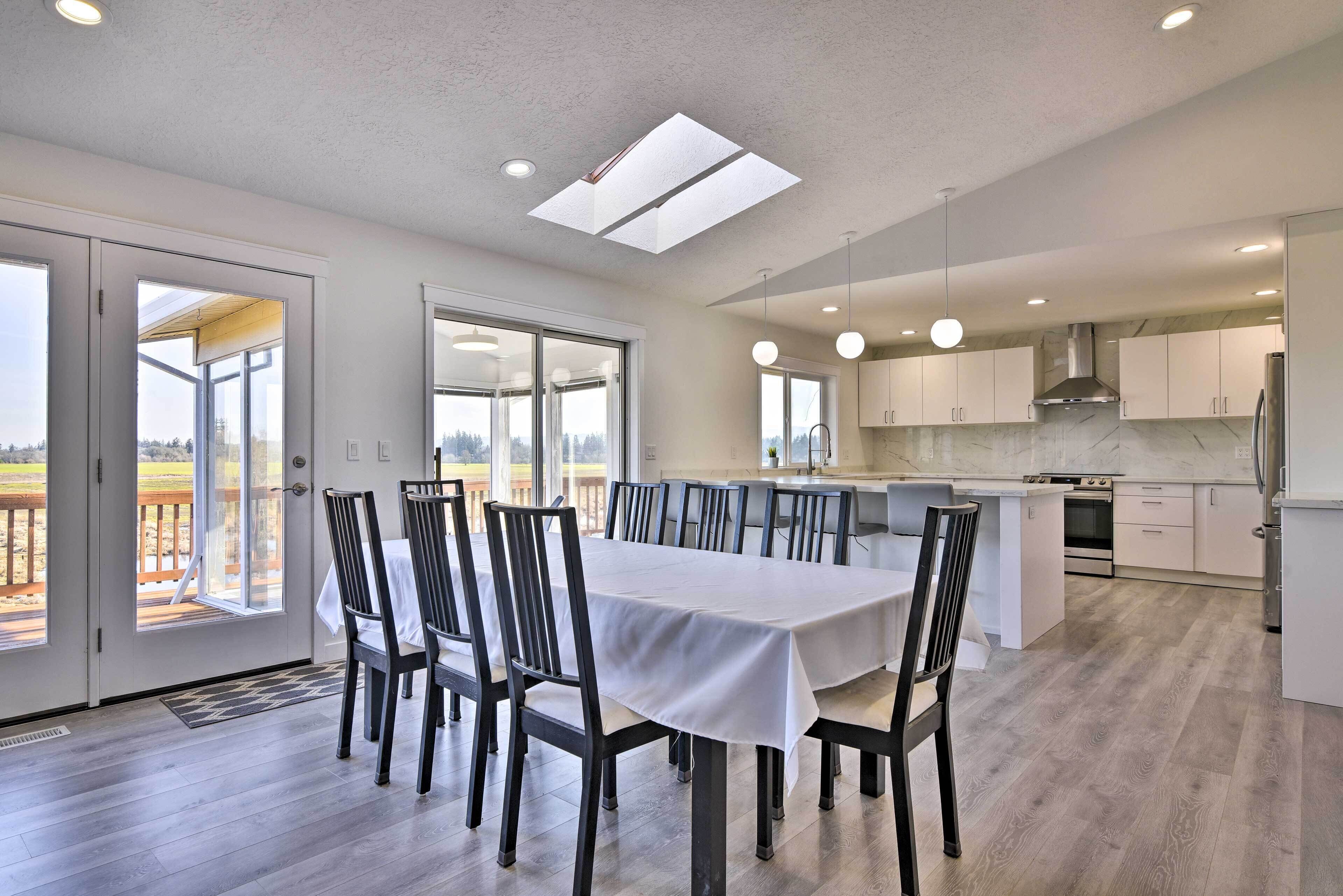 A modern kitchen with white cabinets, a central island, and a dining area with a table and chairs.