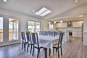 A modern kitchen with white cabinets, a central island, and a dining area with a table and chairs.