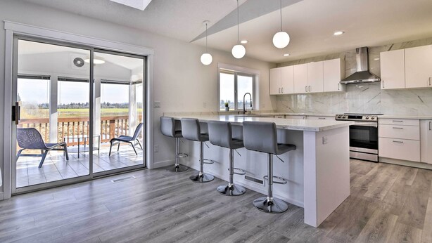Een moderne keuken met een groot eiland, barstoelen en een schuifdeur naar een terras.