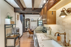 A kitchen with wooden beams, a granite countertop, a sink, and a coffee machine.