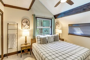 A bedroom with a bed, two bedside tables, a window with curtains, a ceiling fan, and a wall-mounted lamp. - Woodsy Flagstaff Hideaway w/ Deck + Sunroom! (Flagstaff)