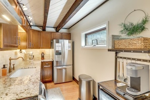 A modern kitchen with stainless steel appliances, wooden cabinets, a marble countertop, and a window with a view. - Woodsy Flagstaff Hideaway w/ Deck + Sunroom! (Flagstaff)