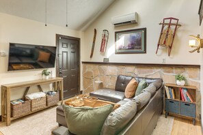 Una sala de estar con un sofá de cuero, televisor, chimenea y estantería.