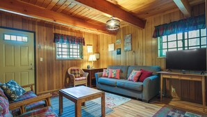 A cozy cabin-style room with a wooden interior, a sofa, a loveseat, a small table, and a television. - Hike, Bike & Golf: Peaceful Cabin in Twain Harte! (Twain Harte)