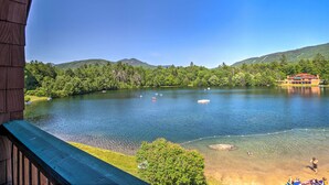 A lake with boats, a wooden building, and a red-roofed structure in the background. - Resort Condo w/ Lake + Pool ~ 5 Mi to Flume Gorge! (North Woodstock)