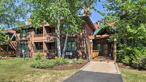 A two-story lodge with a red roof, a balcony, and a front entrance. - Resort Condo w/ Lake + Pool ~ 5 Mi to Flume Gorge! (North Woodstock)