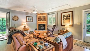 Ein gemütliches Wohnzimmer mit Kamin, Ledersofa, Holztisch und Deckenventilator.