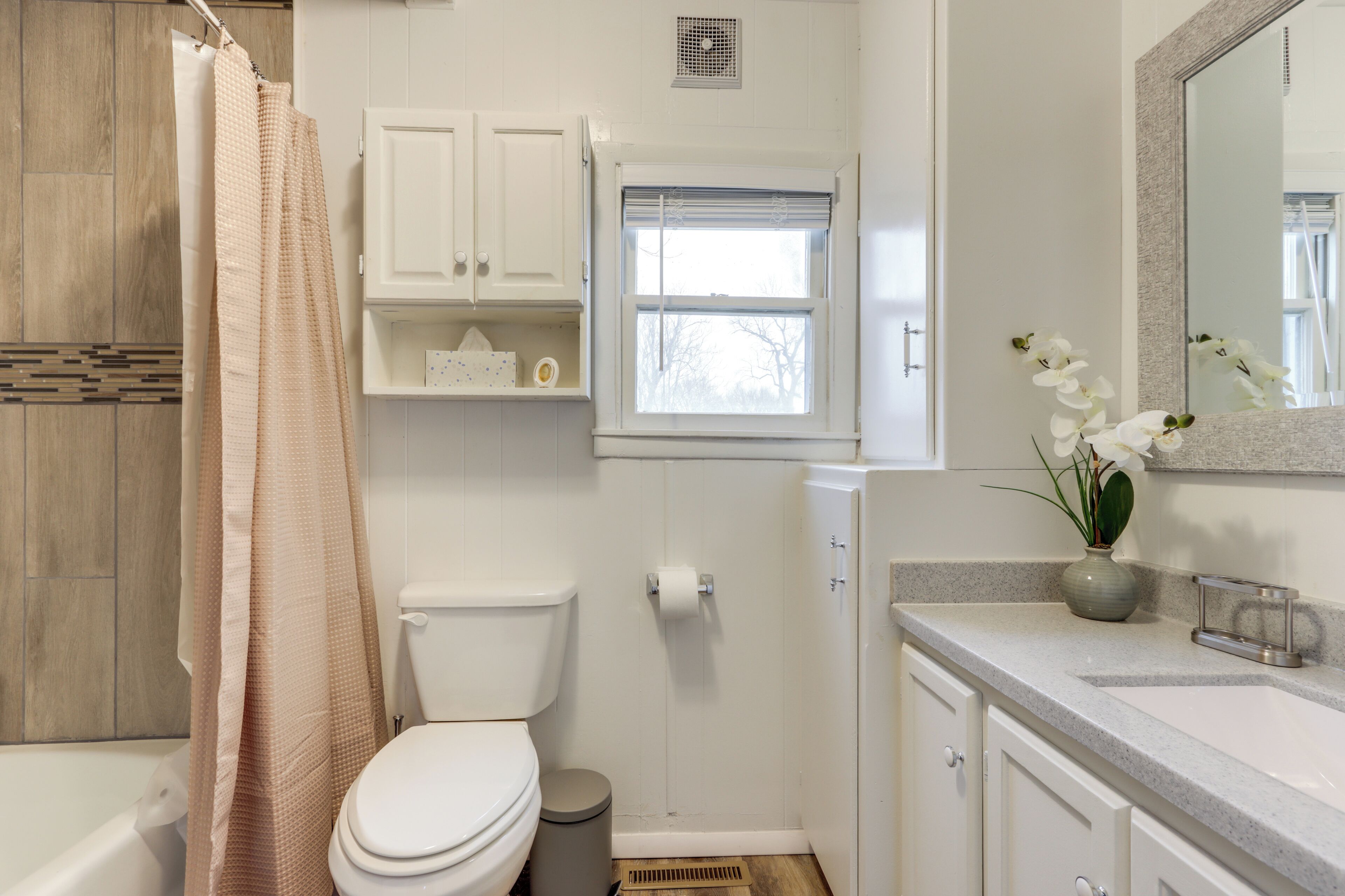 A bathroom with a toilet, shower, and sink area.