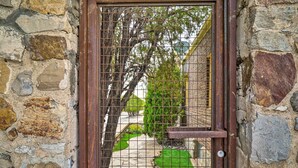 A stone wall with a metal gate and a stone pathway leading to a green lawn.