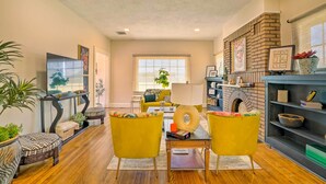 A living room with a fireplace, yellow armchairs, a coffee table, and a large window.