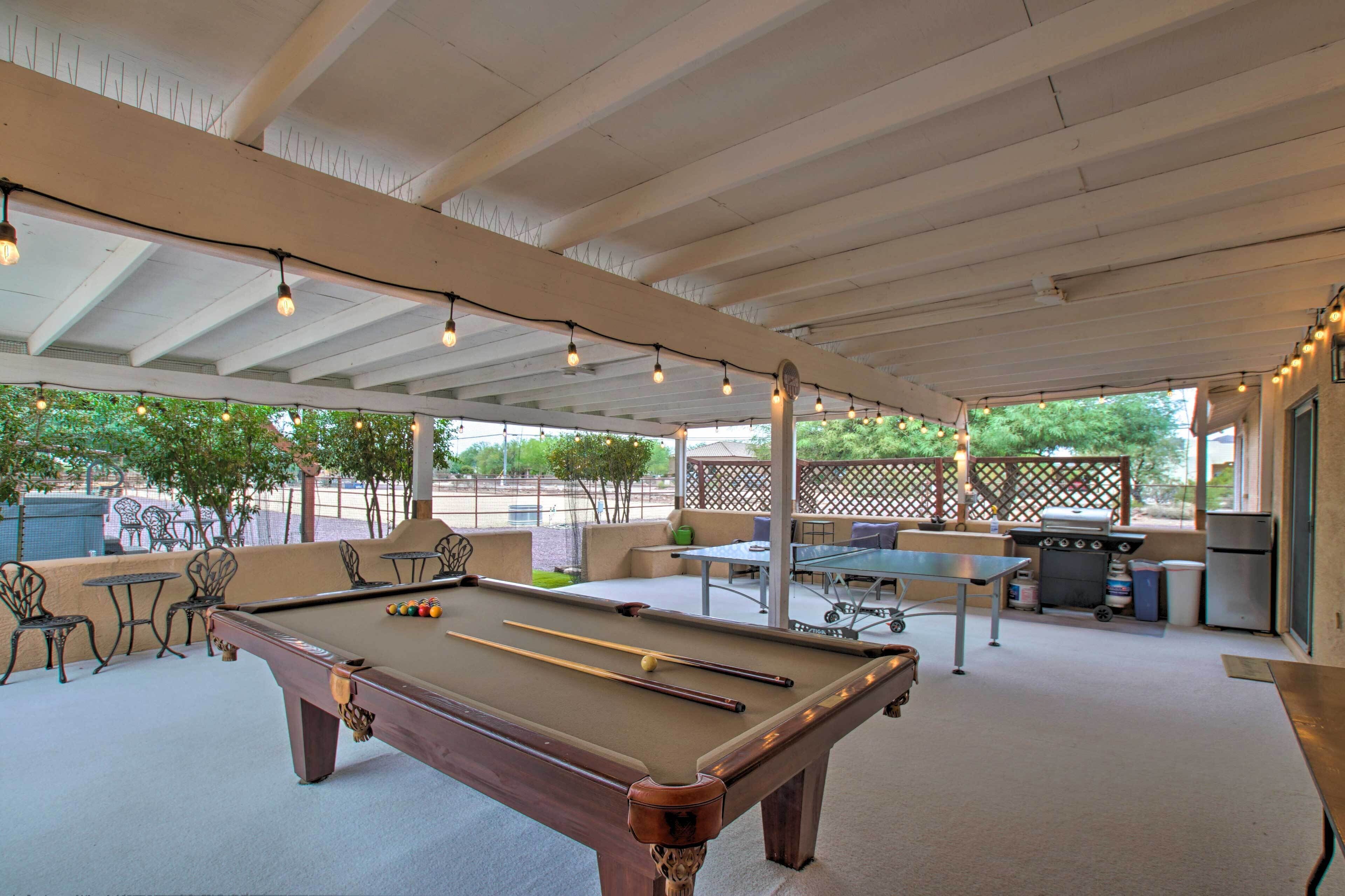 Un espace extérieur avec une piscine, une table de billard, des sièges et un barbecue.