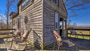 A wooden cabin with a porch, rocking chairs, and a view of the surrounding landscape. - Cabin on Working Highland Cattle Farm in Kentucky (Annville)