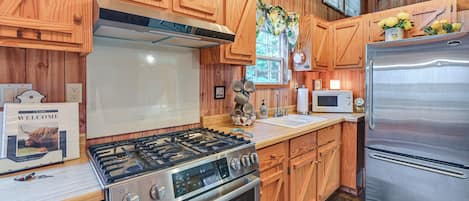 A kitchen with wooden cabinets, a stainless steel stove, a refrigerator, and a microwave.