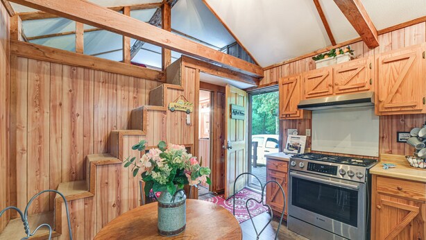 A wooden interior with a round table, chairs, a stove, and a sink. - Cabin on Working Highland Cattle Farm in Kentucky (Annville)