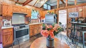 A kitchen with wooden cabinets, a stainless steel refrigerator, a stove, and a coffee bar area. - Cabin on Working Highland Cattle Farm in Kentucky (Annville)