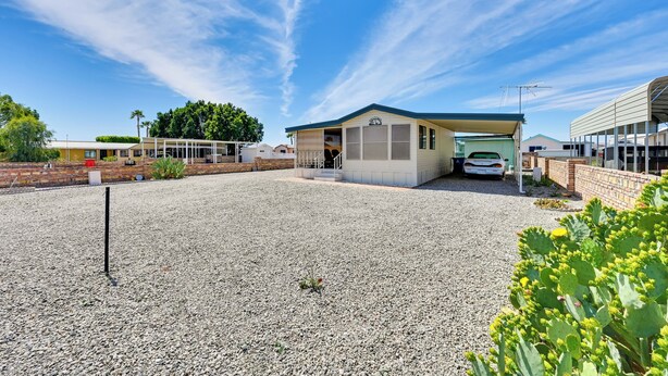 A building with a covered entrance, a gravel driveway, and a parked car. - Pet-friendly Vacation Rental in Yuma With Grill! (Yuma)