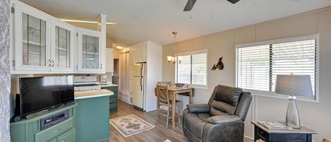 A spacious living area with a sofa, a television, and a dining table with chairs.