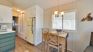 A compact kitchen with white cabinets, a wooden dining table, and a hanging light fixture. - Pet-friendly Vacation Rental in Yuma With Grill! (Yuma)