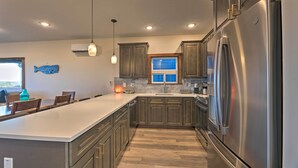A modern kitchen with a large island, stainless steel appliances, and wooden cabinets. - Sanderling Sea Cottages, Unit 6 w/ Beach Access! (Waldport)