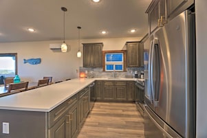 Una cocina moderna con una isla grande, electrodomésticos de acero inoxidable y armarios de madera.