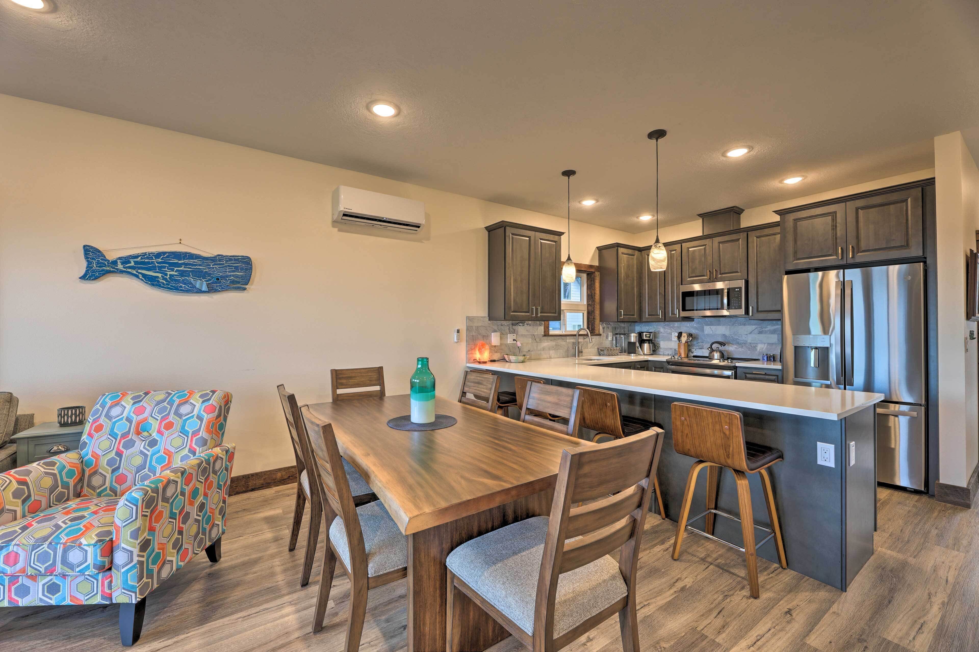 A modern kitchen with dark cabinets, stainless steel appliances, and a wooden dining table with chairs.