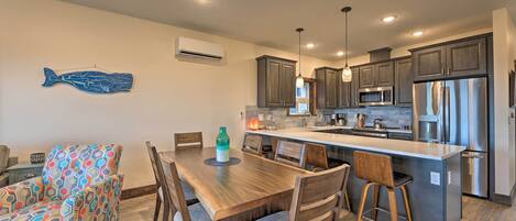 A modern kitchen with dark cabinets, stainless steel appliances, and a wooden dining table with chairs.