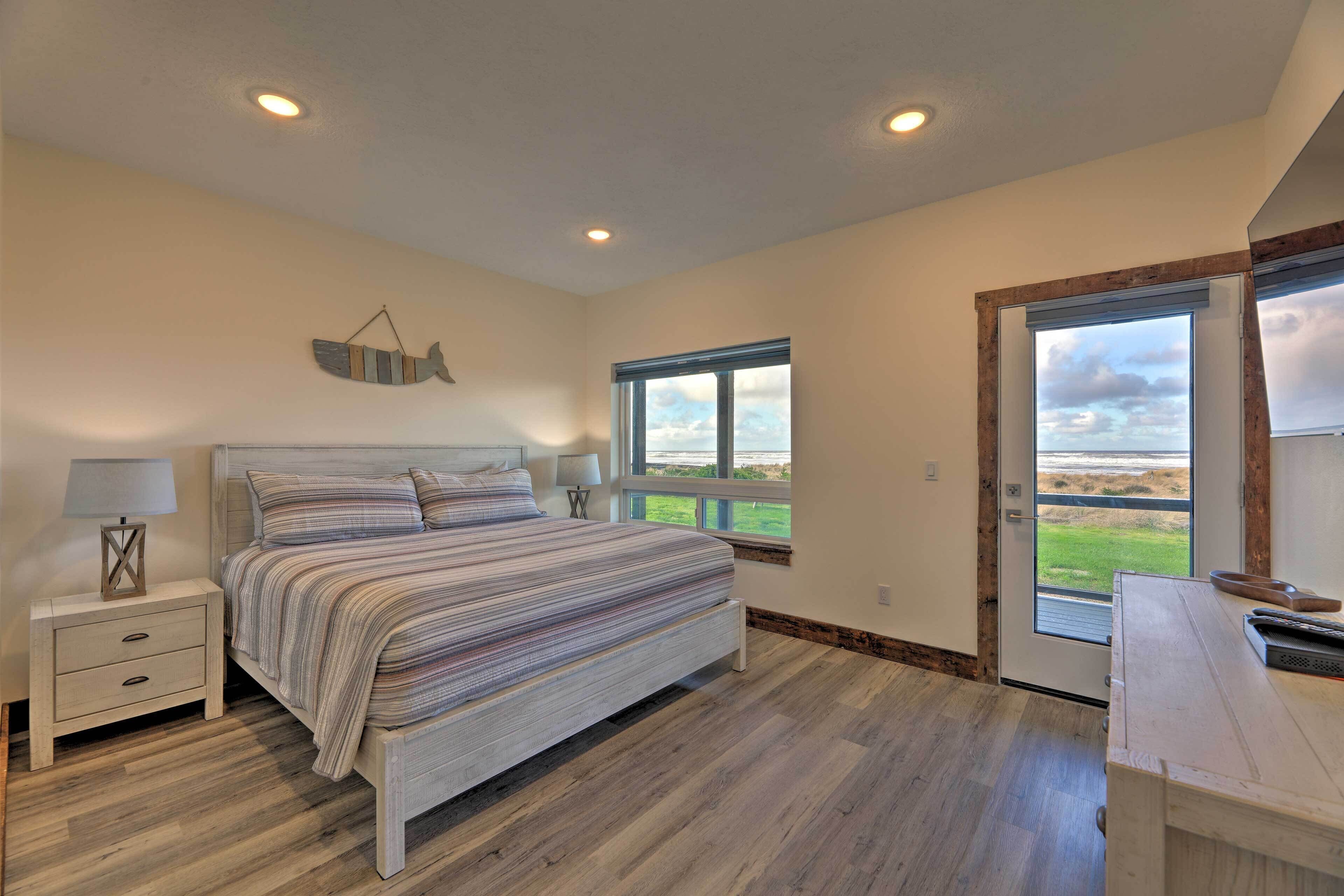 A bedroom with a bed, bedside tables, a window with a view, and a door leading outside.