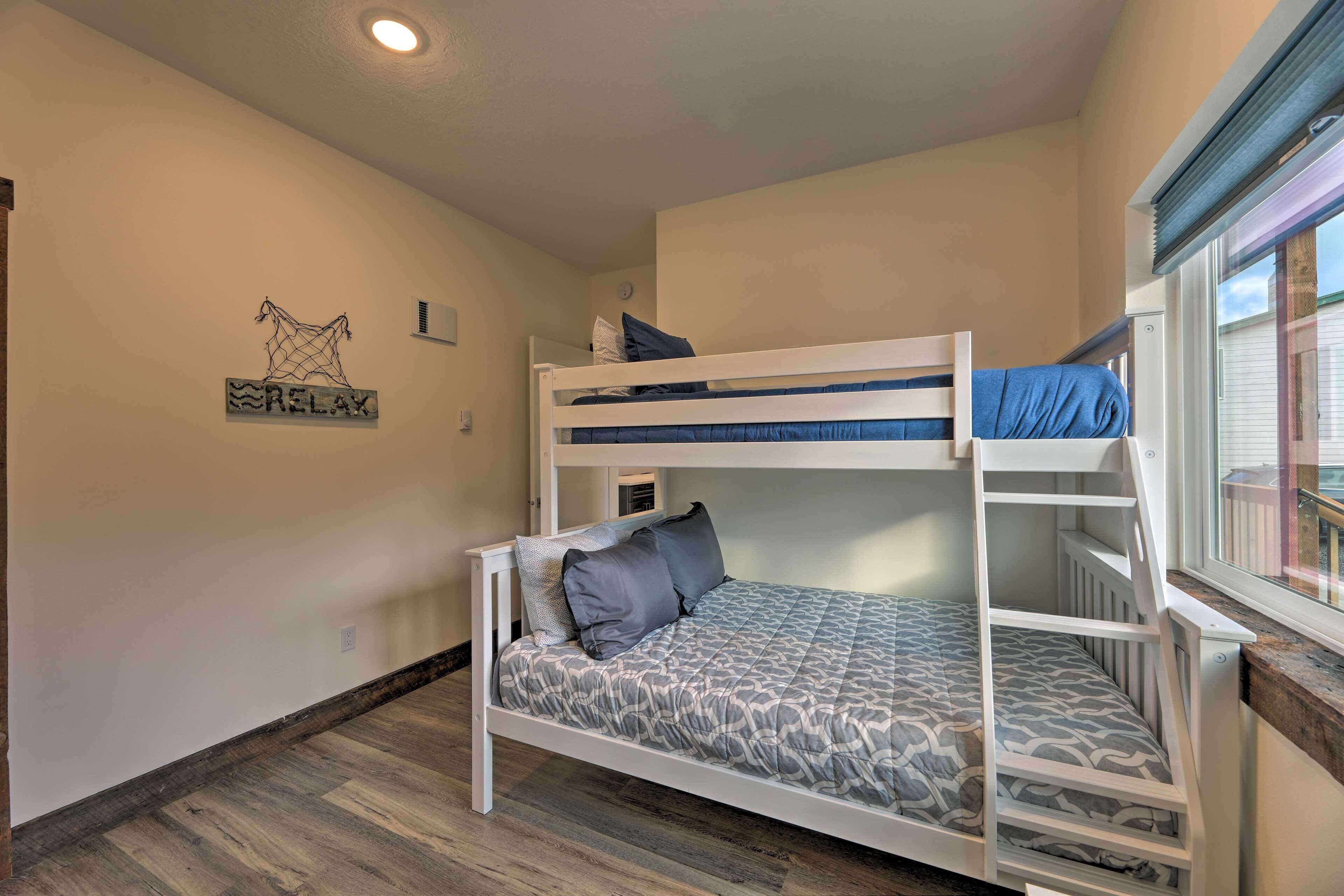 A bunk bed room with a window, a wall decoration, and a wooden floor.