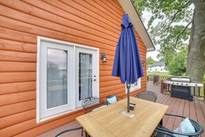 A wooden deck with a table and chairs, a barbecue grill, and a covered patio area. - Charming Curtis House: Large Deck w/ Lake View! (Curtis)