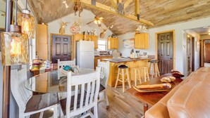 A rustic kitchen with wooden beams, a glass dining table, and a leather sofa.