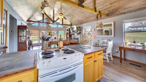 A spacious kitchen with a large island, wooden ceiling beams, and a view of the outdoors.