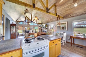 Una cocina amplia con una isla grande, vigas de madera en el techo y vistas al exterior.