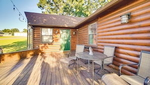 A wooden cabin with a porch, a green door, and a table with chairs.