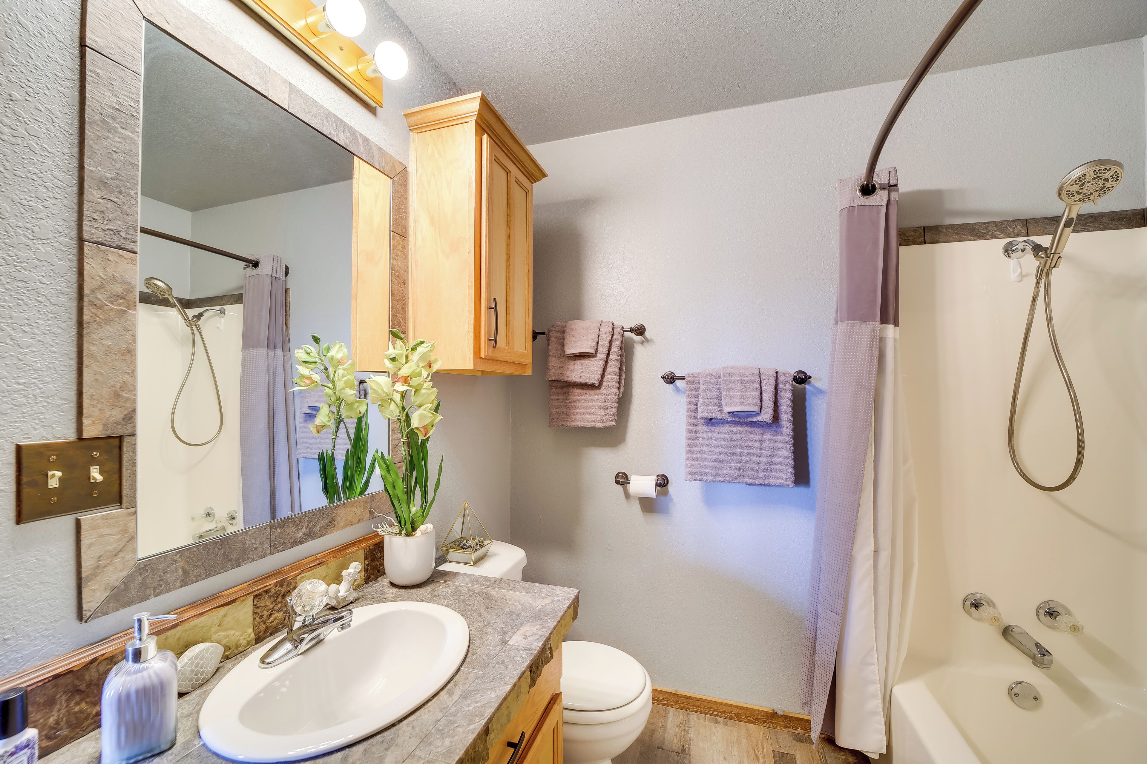 A bathroom with a sink, mirror, cabinet, toilet, and shower.