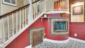 A grand staircase with white balustrades, a decorative fireplace, and a tiled floor. - Luxe Atwater Home w/ Patio: 10 Mi to Yosemite Lake (Atwater)