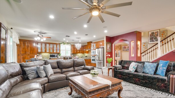 A spacious living room with a large brown leather sectional sofa, a wooden coffee table, and a chandelier. - Luxe Atwater Home w/ Patio: 10 Mi to Yosemite Lake (Atwater)