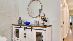 Un mueble de madera blanca con tiradores negros y un espejo encima.