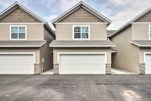 A row of two-story houses with attached garages, featuring a uniform architectural style with beige siding and stone accents. - Gull Lake Winter Escape: Hot Tub & ORV Trails (Nisswa)