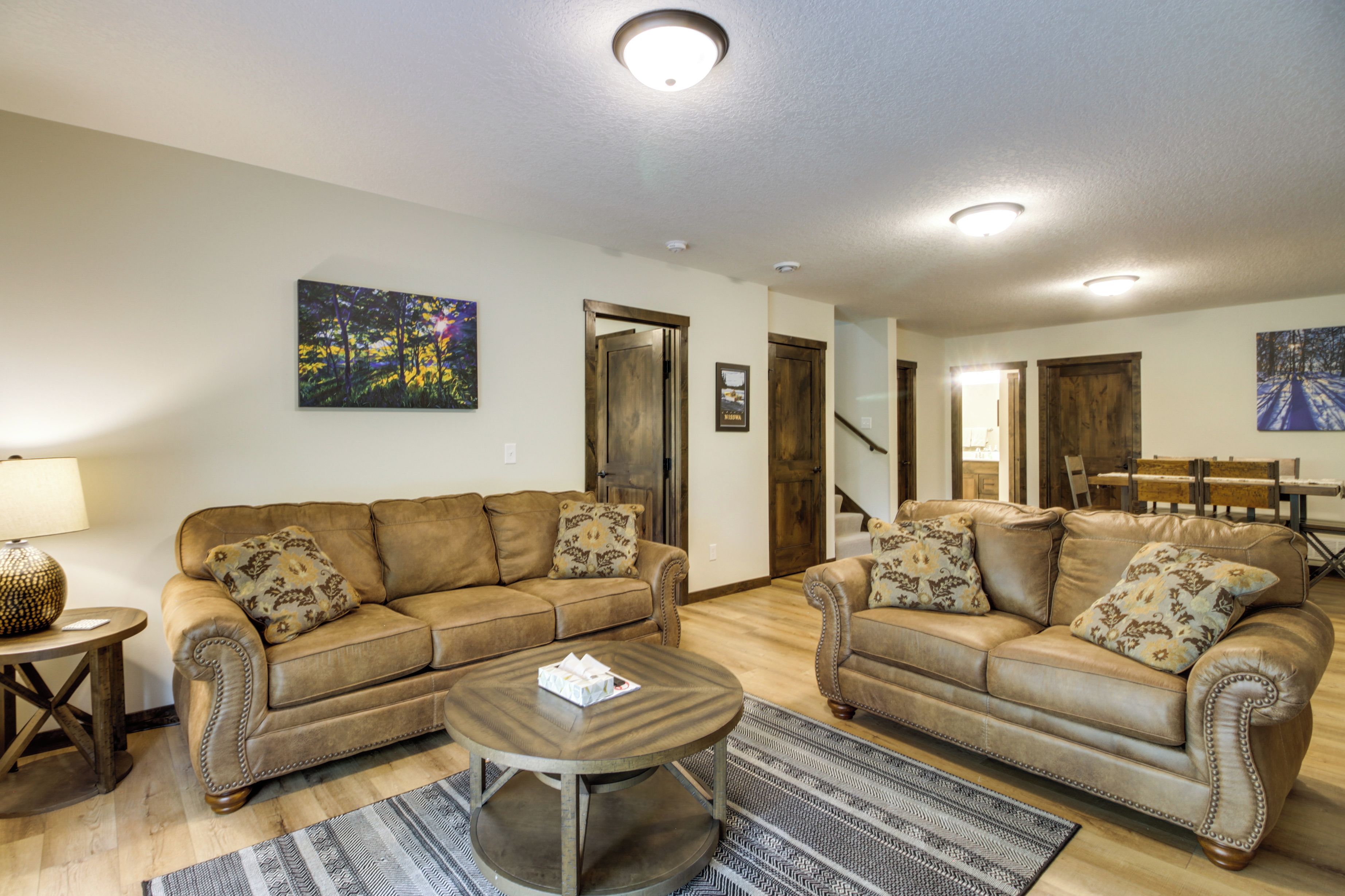 A living room with two brown leather sofas, a wooden coffee table, and a patterned rug.