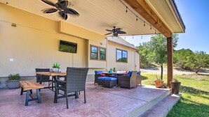 An outdoor patio with a table and chairs, a ceiling fan, and potted plants. - Game Room + 1-acre Yard! Lake Travis Retreat (Leander)
