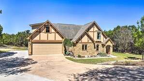 A two-story house with a garage, stone exterior, and a well-maintained lawn. - Game Room + 1-acre Yard! Lake Travis Retreat (Leander)