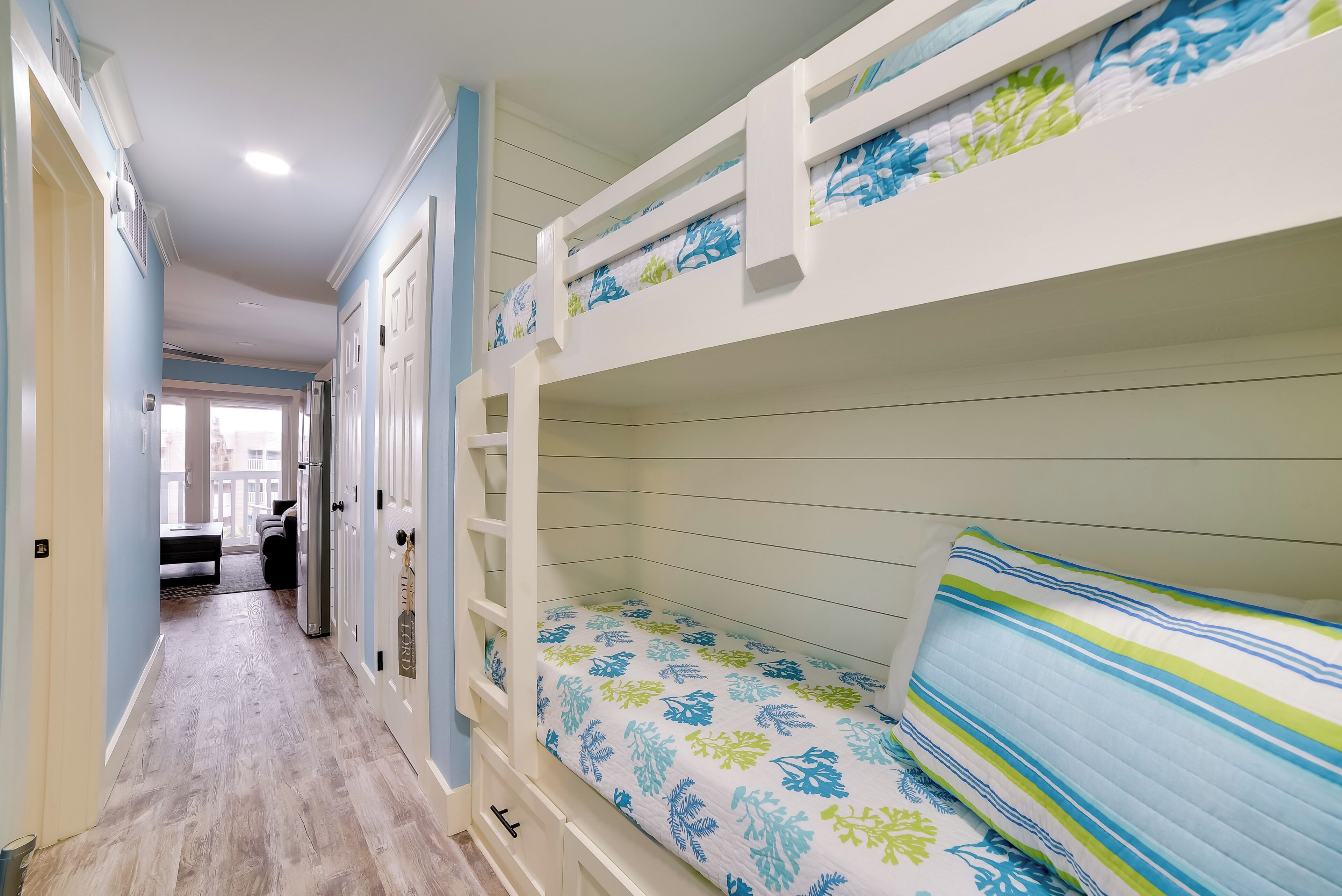 A bunk bed room with a wooden floor and a view to the outside.