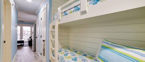 A bunk bed room with a wooden floor and a view to the outside.