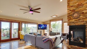Un salón amplio con chimenea, ventilador de techo y televisor.