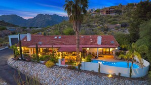 Una casa moderna con piscina, rodeada de un paisaje rocoso y montañas al fondo.