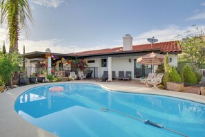 A swimming pool with lounge chairs and umbrellas, surrounded by a house with a tiled roof and a satellite dish. - Luxe Catalina Foothills Hideaway w/ Private Pool (Tucson)