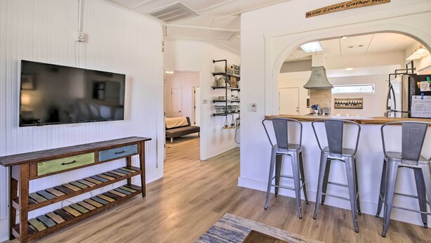 Une cuisine moderne avec un coin bar, un plancher en bois et un téléviseur fixé au mur.