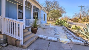 Une maison avec un porche, des marches et un jardin agrémenté de cactus et d’un banc.