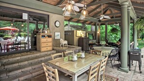 Un patio al aire libre con una mesa de comedor, sillas y una encimera de cocina.